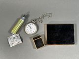 une petite boîte avec une horloge et un briquet à côté