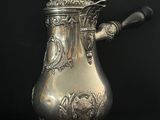 une cafetière en argent avec une anse, sur fond noir