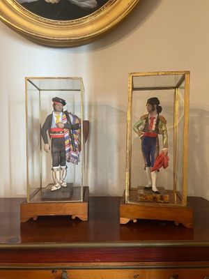 deux figurines représentant des hommes, exposées dans des vitrines posées sur une commode