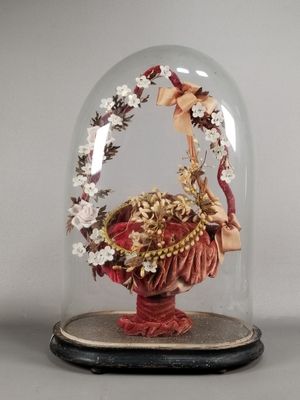 a glass dome with a figurine of a woman holding a basket of flowers