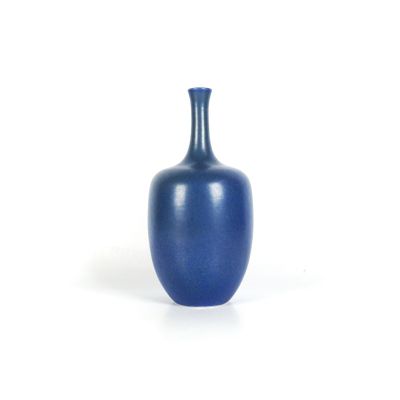 un vase bleu posé sur une surface blanche