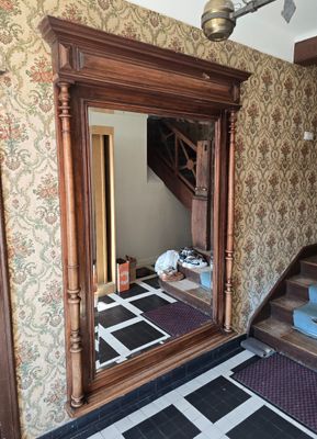 un grand miroir au milieu d'une pièce où se trouve un escalier