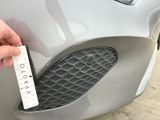 a hand that is holding a ruler to the front of a car