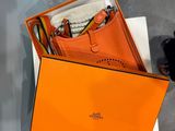 orange hermes bag with matching wallet and other items in it