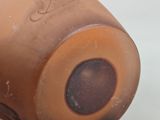 a close up of a brown vase on a white surface
