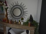 a mirror on the wall above a fireplace with a vase of flowers