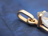 a close up picture of a diamond pendant on a blue cloth