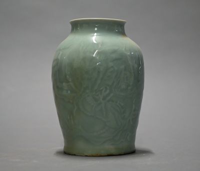 a green vase sitting on a table with a gray background