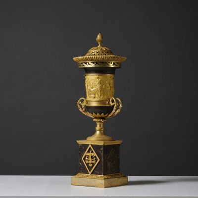 un vase doré et noir posé sur une table blanche