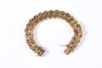 gros plan d'un bracelet en or sur une surface blanche