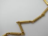 un gros plan d'un collier avec une chaîne en or sur une surface blanche