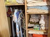 a closet with a lot of clothes and a wicker chair