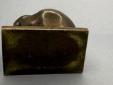 une sculpture en bronze représentant un chat assis sur une boîte