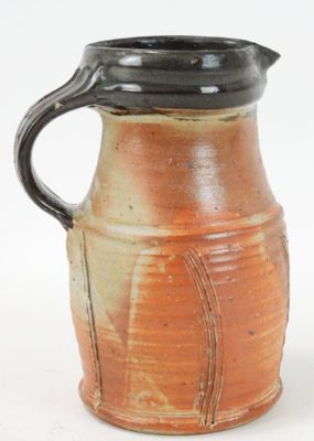 a brown and black vase with a handle on a white background