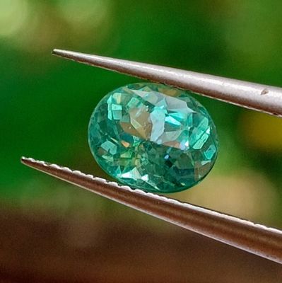 a close up of a green diamond being held by a pair of pliers