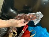 a person holding a bag of donuts in front of a trash can