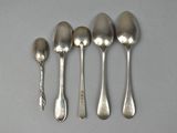 six spoons and a spoon rest on a table