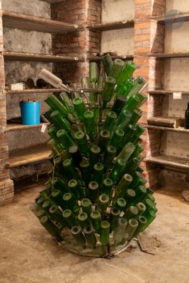 un grand vase en verre rempli de bouteilles vertes, placé au milieu d'une pièce