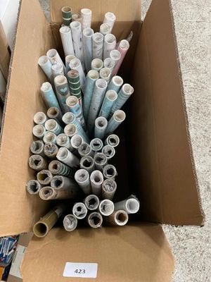 many rolls of paper in a cardboard box on the floor