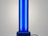 une lampe bleue posée sur un socle blanc, près d'un mur