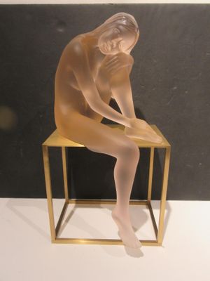 a glass sculpture of a nude woman sitting on a chair