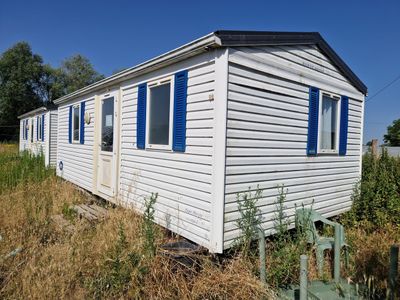 une petite maison blanche aux volets bleus, au milieu d'un champ