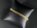un bracelet en or posé sur un coussin noir