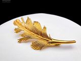 une photo d'une broche en feuille d'or posée sur une assiette blanche