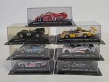 six model cars in a display case on a white surface