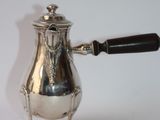 a silver coffee pot with a black handle on a stand