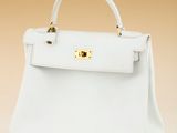 a white handbag with gold hardware on the handle