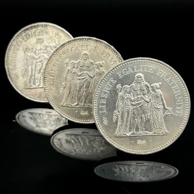 trois pièces d'argent empilées les unes sur les autres sur une surface noire