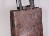 sac à main en peau de serpent marron avec une poignée noire sur fond blanc
