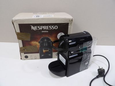 a nespresso machine sitting on a table next to a box of nespresso coffee