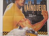 On voit l'affiche du film « Le Vainqueur ».
