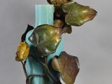 statue représentant un perroquet perché sur une branche d'une plante dans un vase