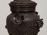 an image of a bronze urn with a bird on top of it