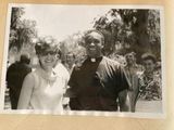 black and white photograph of a priest and a woman in front of a group of people