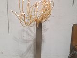 a tall metal vase with a bunch of flowers in it