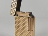 a gold lighter with a black lid sitting on top of a white surface