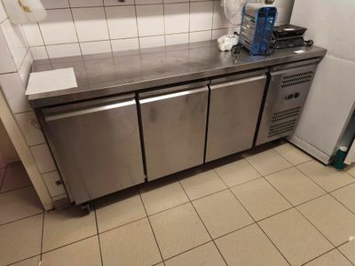 a stainless steel counter top in a kitchen with a refrigerator