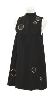 La robe est noire et ornée de cercles argentés.