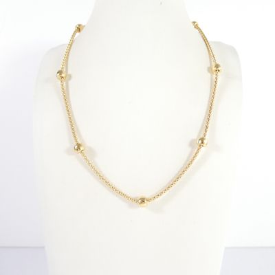 Le collier en perles d'or est exposé sur un mannequin
