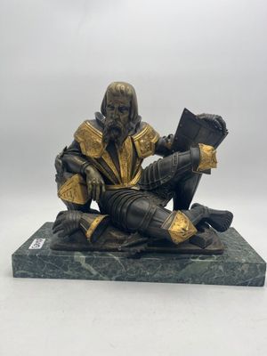 statue of a man reading a book on a marble base