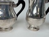 two silver teapots sitting next to each other on a table