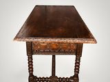 an old wooden table with a carved top and turned legs