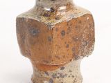 un petit vase posé sur une surface blanche