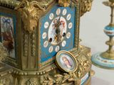 a gold clock sitting on a table with a picture on it