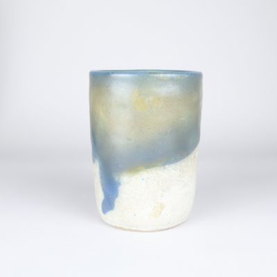 une tasse bleue et blanche posée sur une surface blanche