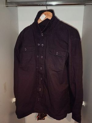 une chemise suspendue à un cintre dans une armoire où se trouvent d'autres vêtements